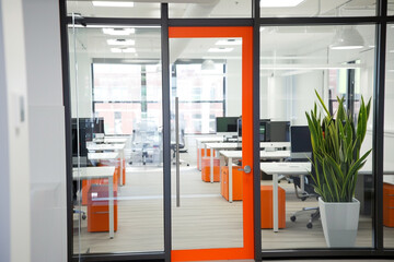Look into an office with orange details and minimalist white desks.