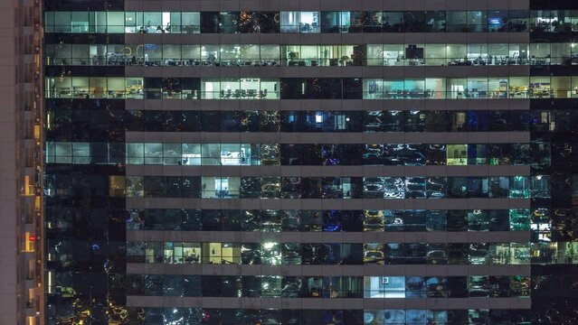 Office buildings windows illuminated at night timelapse. Glass architecture, corporate building at evening with glowing lights