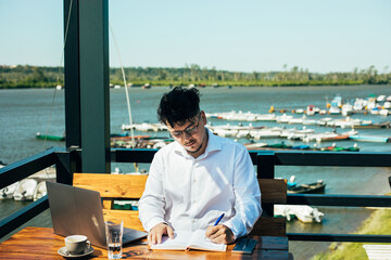A young businessman working in a cafe by the river port