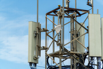 Telephone and internet antennas, on a metal structure against cloudy blue sky