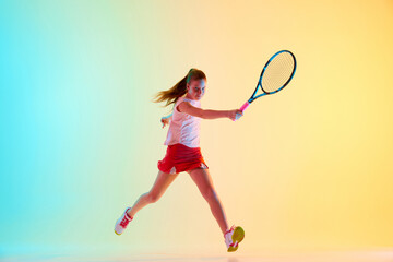 Young tennis player leaps into action , her racket poised to strike a powerful forehand shot in...