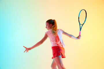 Portrait of focused young girl, tennis player ready to hit ball in motion in neon light against...