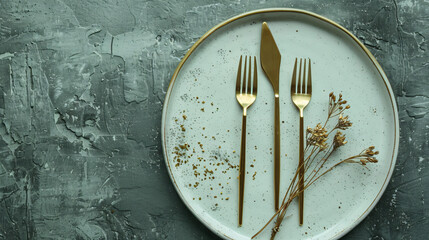 Clean plate with golden cutlery and dried lagurus