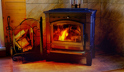 Black metal stove fireplace with wood in a woodpile, cottage, village house. Heating house with firewood. Saving energy on heating. Furnace