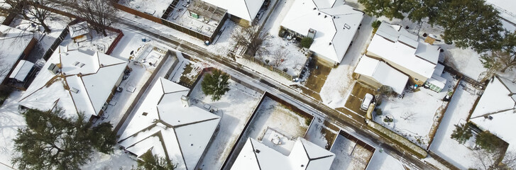 Toned photo residential streets and row of single-family houses covered in snow after severe weather, climate change event in Dallas-Fort Worth metropolitan subdivision, sunshine melting, aerial. USA