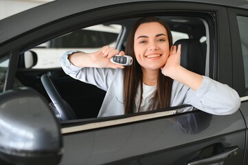 Photo of happy young woman sitting inside her new car. Concept for car rental