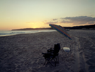 Sunset on the beach: chair, umbrella, surfboard and sand. Medium format film (Kodak Ektar 100) shot...