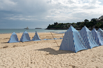 blue and white striped canvas beach tents on the beach of Dinard, Brittany, France