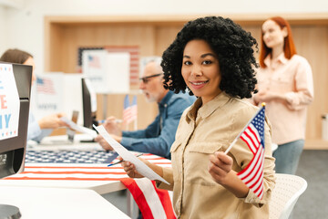 Portrait of smiling African American woman, voter holding American flag and ballot paper