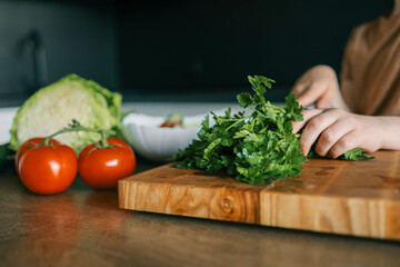 Child at table with leaf vegetables, a natural food ingredient
