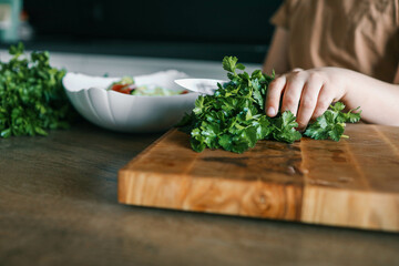 Child is using a cutting board to chop vegetables for a dish