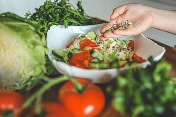 Preparing vegetable salad, sprinkle flax and sesame seeds