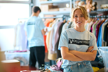 Portrait Of Female Charity Worker Sorting Clothing Donations At Thrift Store