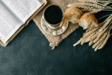 Cup with wine, bread and open Bible, Christian communion