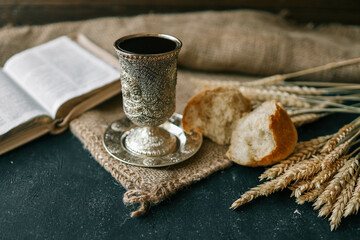 Cup with wine, bread and open Bible, Christian communion