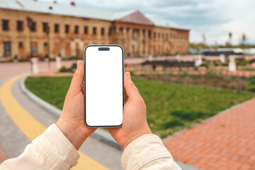 Phone in hands with isolated screen against the background of a restored building