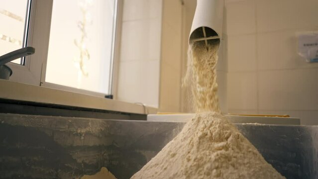 outline of the process of pouring flour through a tube into an iron container in professional kitchen