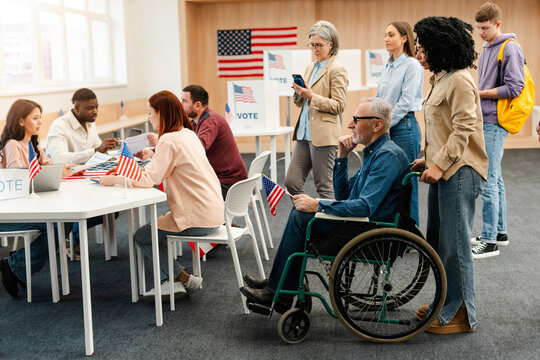 Group of diverse US citizens performing civic responsibility waiting in line at polling station