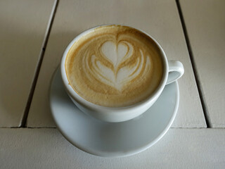 Cup of coffee cappuccino on the white table - nicely decorated on top