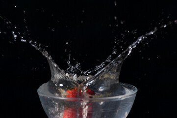 Fraise que tombe dans un bol d'eau et éclabousse