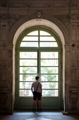 Homme de dos devant une immense porte vitrée ancienne