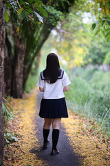 Japanese high school student walking in park with tree background