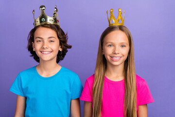Photo of funky cheerful friends wear t-shirts golden tiaras smiling isolated violet color background