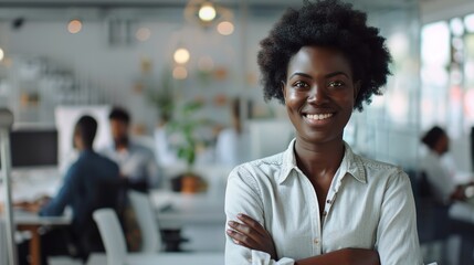 Fototapeta premium Happy Small Business Owner Black African Woman Posing with Hands Folded - Employees Working in Modern Office Behind. Millennial Female Team Leader at Workplace 