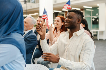 Group of positive, multinational people, US citizens holding American flag, applauding, meeting
