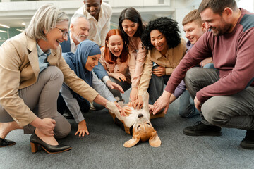 Smiling multiethnic people, business team petting dog together, resting, team building in office