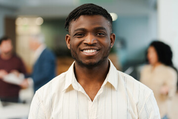 Fototapeta premium Attractive African American young man businessman looking at camera posing in modern office