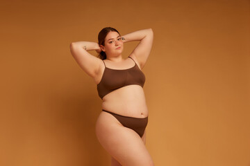 Beautiful young girl feeling confident in her natural, plus size body, standing in underwear...
