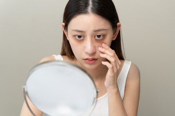 Bored, insomnia asian young woman, girl looking at mirror hand touching under eyes with problem of...