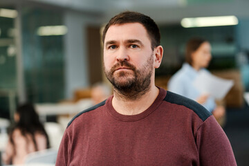 Serious middle aged bearded man, manager, employee looking at camera working in modern office