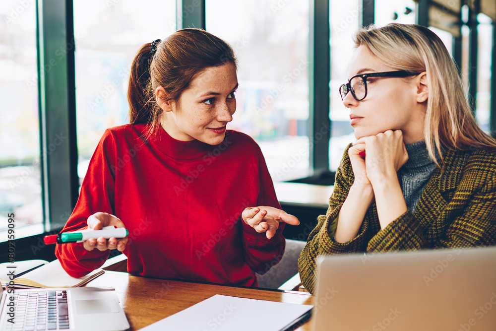 Poster skilled female designer explaining productivity ideas while professional colleague attentively liste