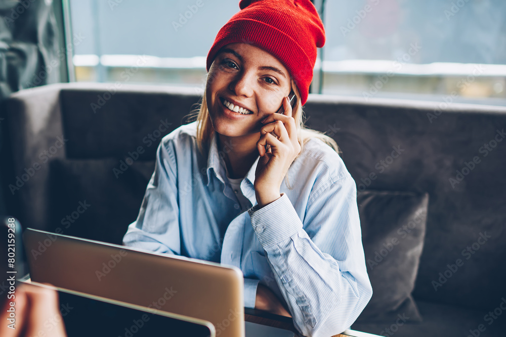 Poster portrait of successful female freelancer in stylish red hat talking calling to mobile operator and t