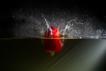 A red bell pepper falls into the water. A splash of water.