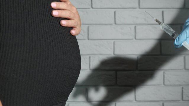Sick pregnant with injection. A view of woman with pregnant belly by the doctor with injection. A concept of health problems during pregnancy and contraception trouble.
