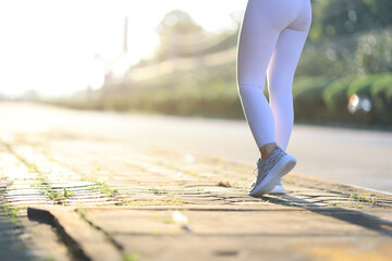 Legs of a female runner are jogging on the footpath in the park.