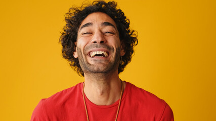Close up, laughing attractive man with curly hair, dressed in red T-shirt, looking at camera and...