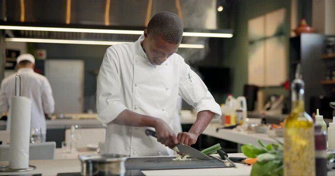 Man, chef and chopping vegetables in kitchen as professional cook, restaurant or meal prep. Male person, knife and culinary hospitality for fine dining dinner for healthy nutrition, food or cuisine