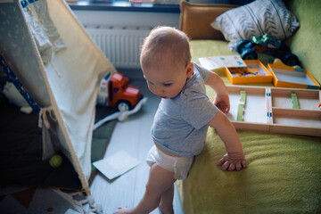 curious toddler boy staying near baby wigwam at home 