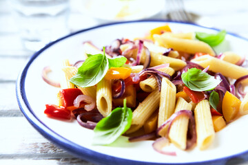 Penne pasta with yellow and red pepper, hard cheese and fresh basil. Bright background. Close up.	
