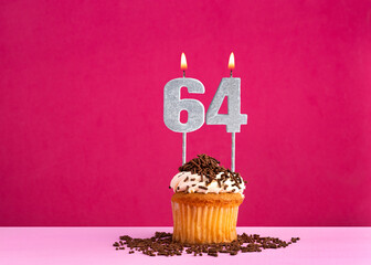 Birthday cupcake with candle number 64 - Birthday card on pink background