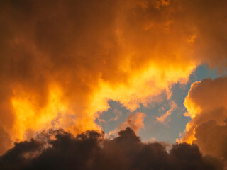 Several cumulus clouds obscuring most of blue sky during golden hour on an evening early in June, southwest Florida, for motifs of transition and disappearance