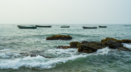 Many small fishing boats and rocks in the sea.