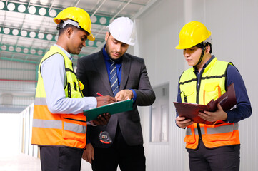 Engineers and employees wear safety helmets working inside the factory.