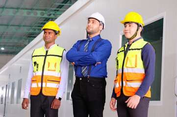 Engineer, employee wearing safety helmet standing and smiling.