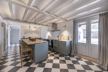 Kitchen with central island with wooden countertops and large wooden furniture in military blue,...