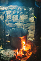 A large cauldron perched on top of a roaring fire, emitting billows of smoke as it heats up a...